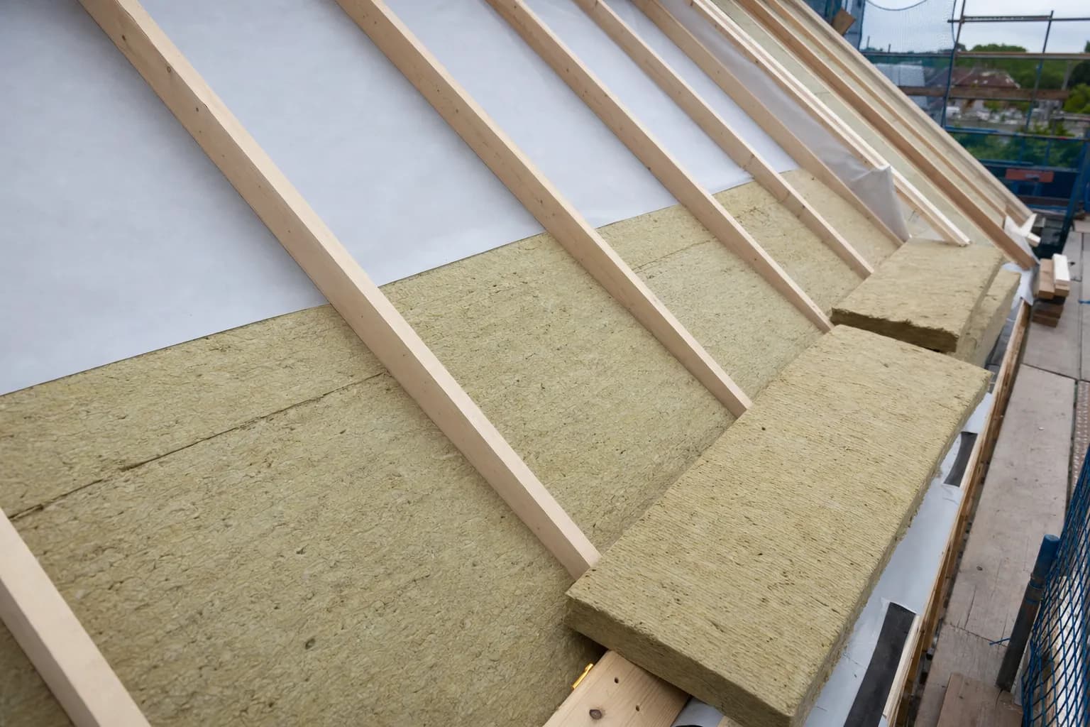Zimmerer von Blang Holzbau bringt Zwischensparrendämmung in einem Dachstuhl aus Holz an